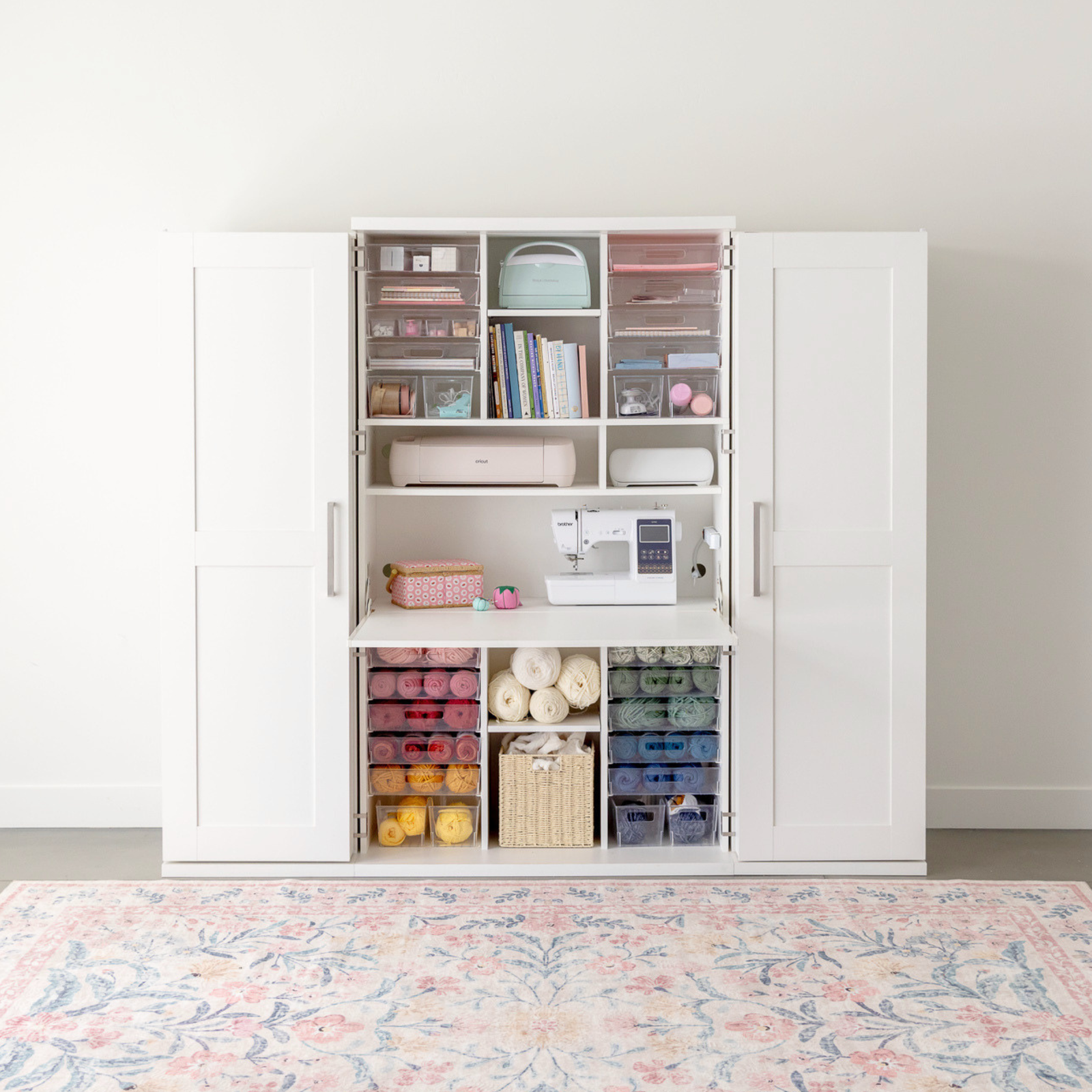 White storage cabinet with a sewing machine and yarn inside acrylic storage bins White storage cabinet with a sewing machine and yarn inside acrylic storage bins