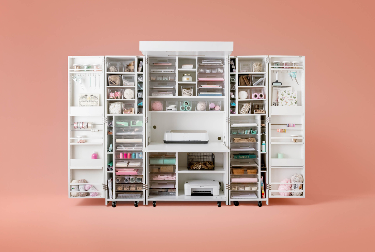 A white DreamBox storage system with various compartments and shelves, partially filled with items, set against a pink background.