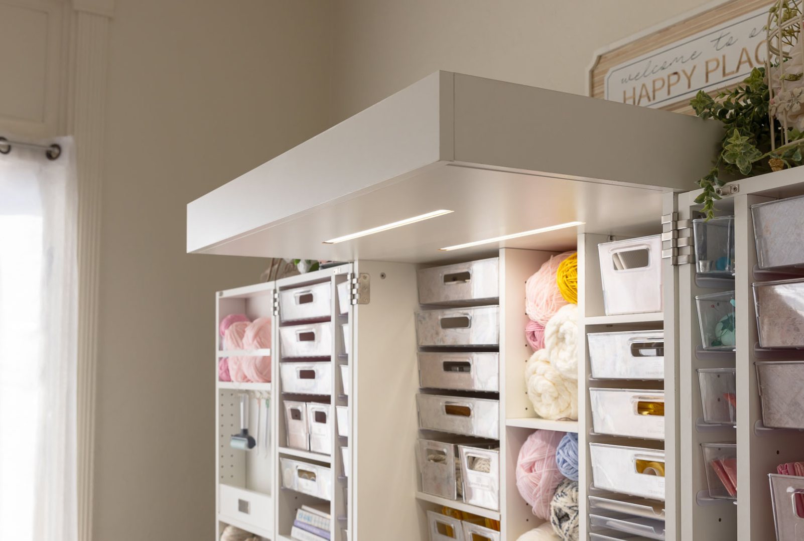 Storage cabinet with shelves and drawers filled with items in a craft room, featuring an overhead light for sewing.