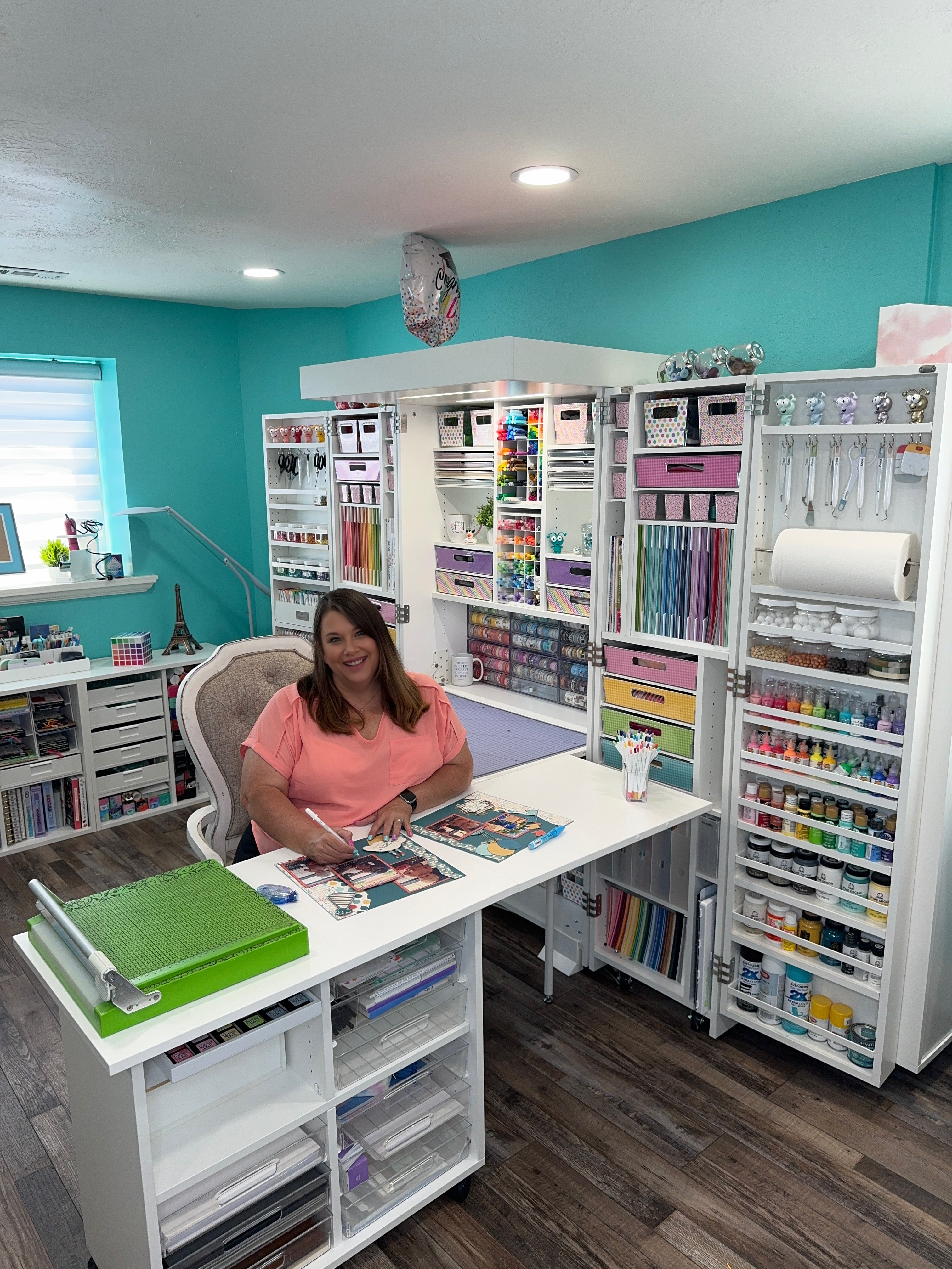 Person in a craft room with organized shelves and supplies using the DreamBox by Create Room.